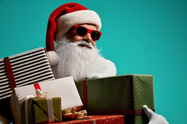 Front view of smiling Santa Claus with white beard showing thumb up. Isolated portrait of handsome senior man in christmas costume and glasses posing Concept of holidays.