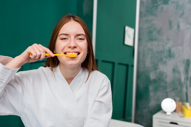 Front view of smiling woman brushing her teeth