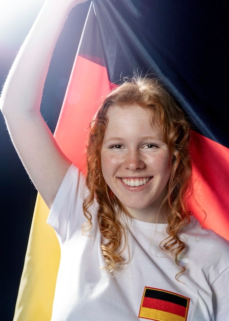 Front view of smiling woman holding german flag