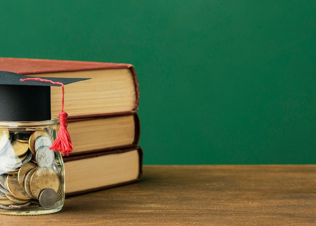 Free photo front view of stack of books with copy space and jar of coins