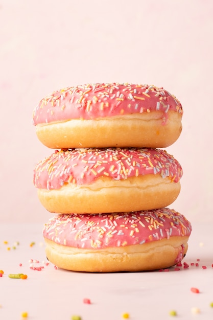 Front view of stack of doughnuts with colorful sprinkles and glazing