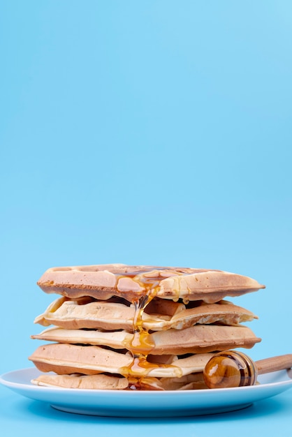 Free photo front view of stack of waffles covered in honey with copy space