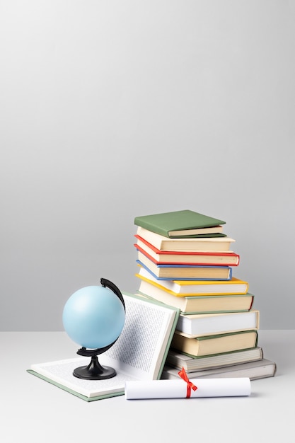 Free photo front view of stacked books, a diploma and an earth globe with copy space for education day