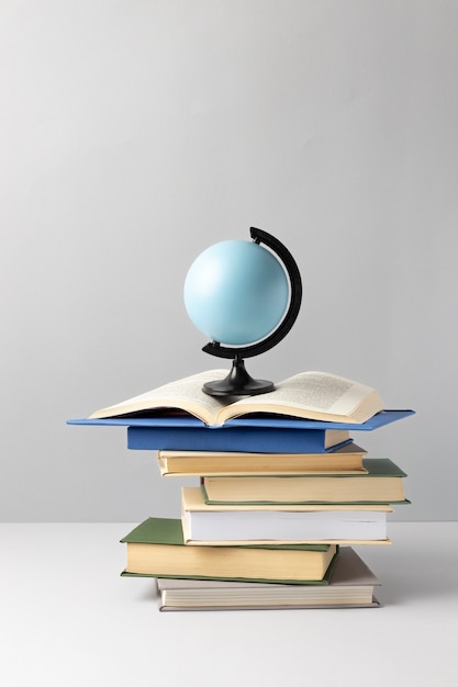 Free photo front view of stacked books, an earth globe and an open book for education day