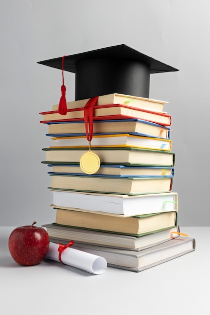 Free Photo front view of stacked books, a graduation cap and a diploma for education day