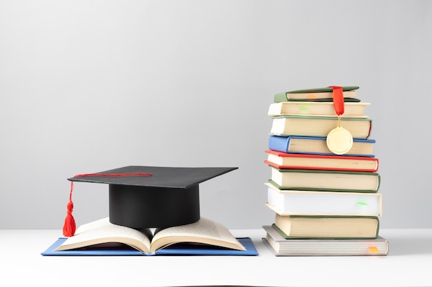 Front view of stacked books, a graduation cap and an open book for education day