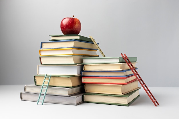 Front view of stacked books, ladders and an apple with copy space for education day