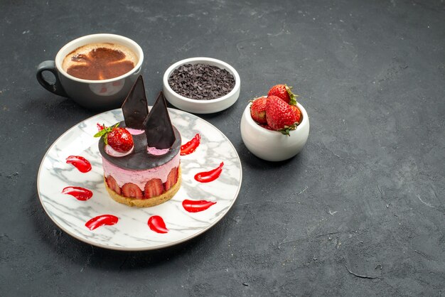 Front view strawberry cheesecake on white plate bowls with strawberries and chocolate a cup of coffee on dark background free space