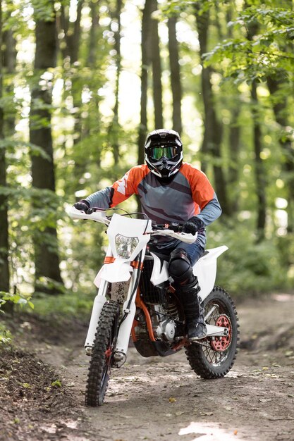 Front view stylish man riding motorbike in the forrest