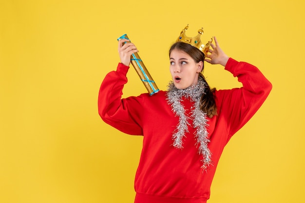 Front view surprised girl with red sweater and crown holding party popper