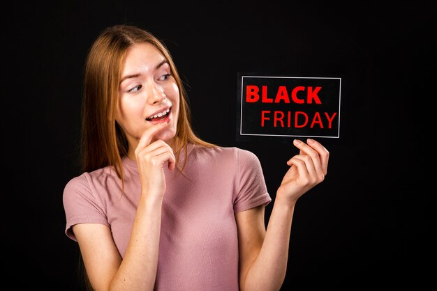 Front view of a surprised woman looking at the black friday card