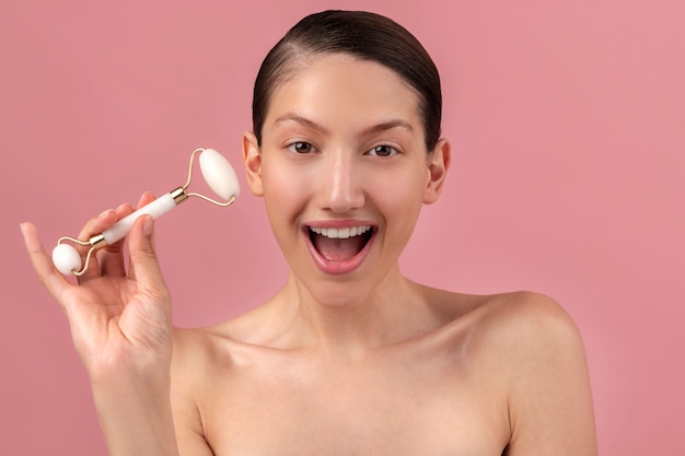 Front view surprised woman with face roller