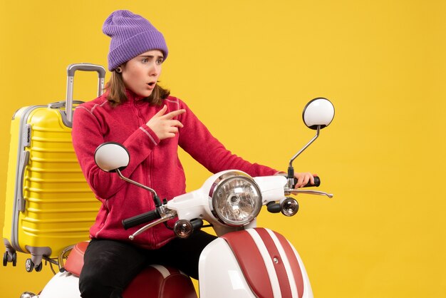 Front view surprised young girl on moped pointing at something