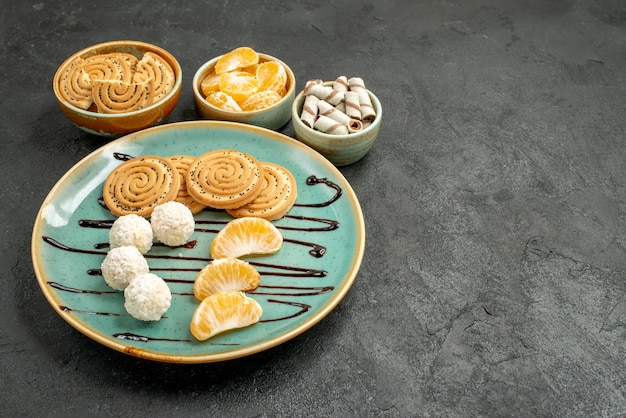 Front view sweet biscuits with coconut candies on a grey desk biscuit cookie sweet