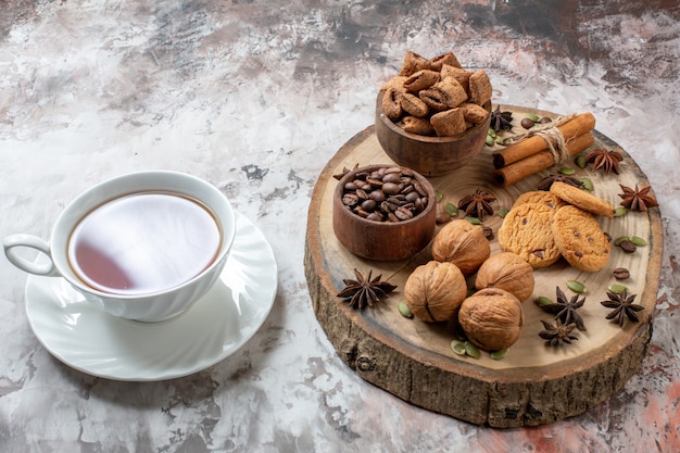 Front view sweet biscuits with cup of tea and walnuts on light background sugar tea color cookie sweet cocoa cake