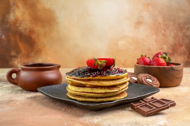 Front view sweet pancakes with cakes and cookies on a wooden desk