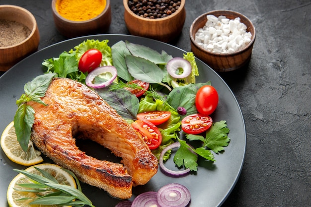 Free photo front view tasty cooked fish with fresh vegetables and seasonings on dark background color food meat seafood dish photo