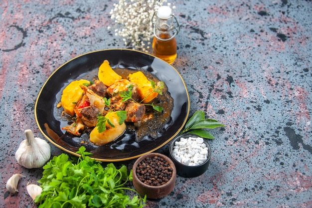 Free photo front view of tasty dinner with meat potatoes served with green in a black plate and spices garlic oil bottle