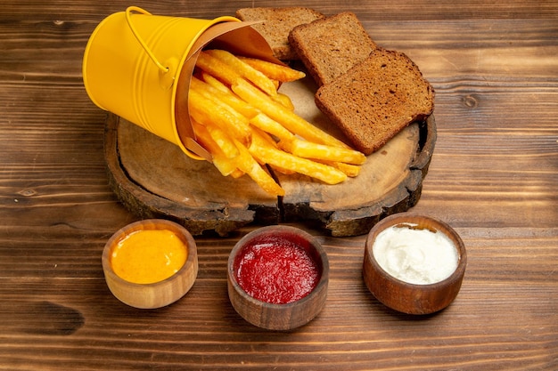 Front view tasty french fries with seasonings on brown desk potato fast-food bread meal