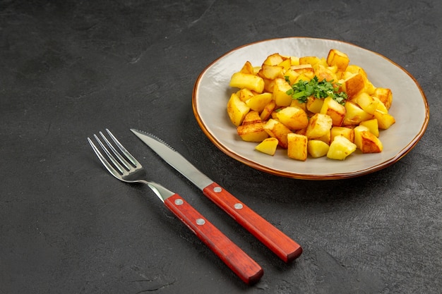 Free Photo front view tasty fried potatoes inside plate with greens on dark table