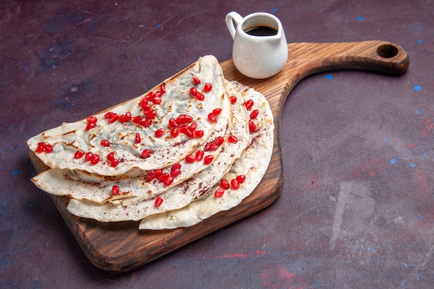 Front view tasty meat qutabs pitas with fresh red pomegranates on dark-purple surface meat dough pita