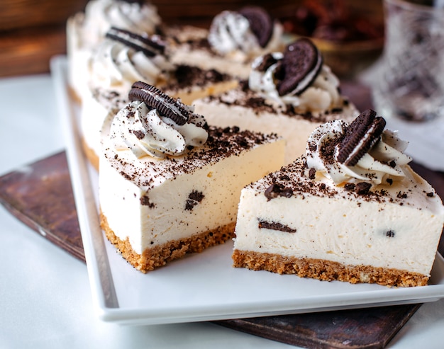 Front view tasty oreo cheesecakes inside white plate on the brown surface