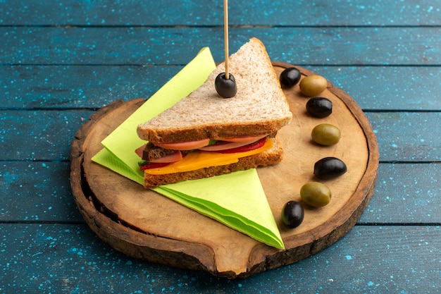 Front view tasty sandwich with cheese ham inside with olives on blue wooden desk