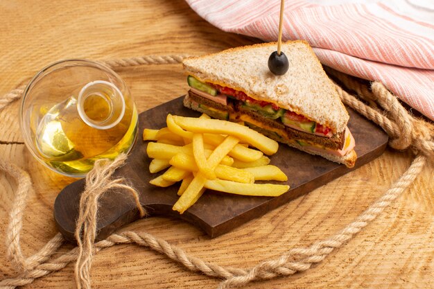 Front view tasty sandwich with olive ham tomatoes vegetables along with french fries ropes oil on wood