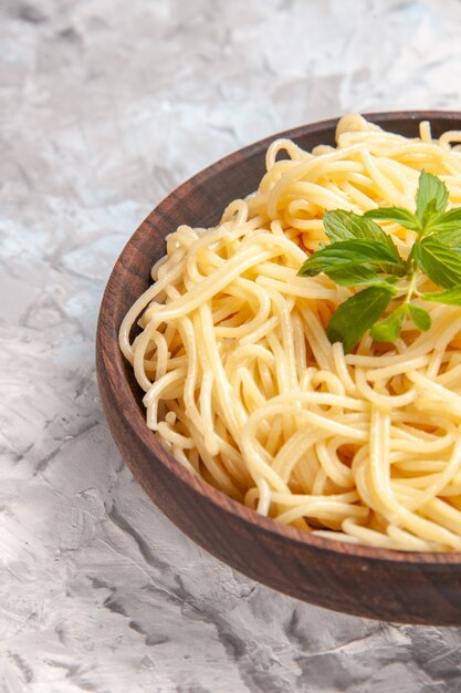 Front view tasty spaghetti with green leaf on white desk meal dish dough pasta