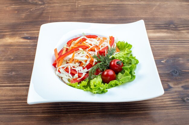 Front view tasty vegetable salad with green salad and cabbage inside plate on brown surface