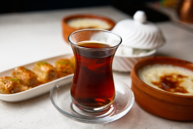 Front view tea in an armudu glass with baklava and sugar on the table