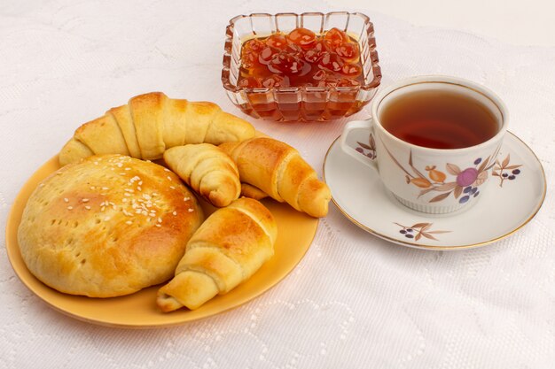 front view tea time croissants biscuits jam and hot tea on the white floor