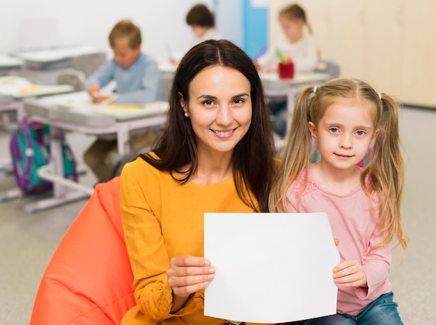 Free photo front view teacher showing an empty piece of paper