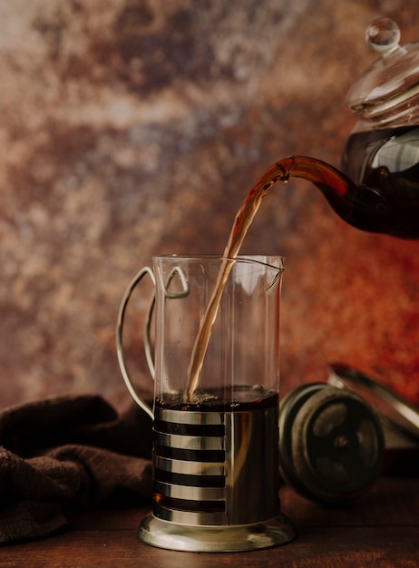 Front view teapot pouring tea in a grinder