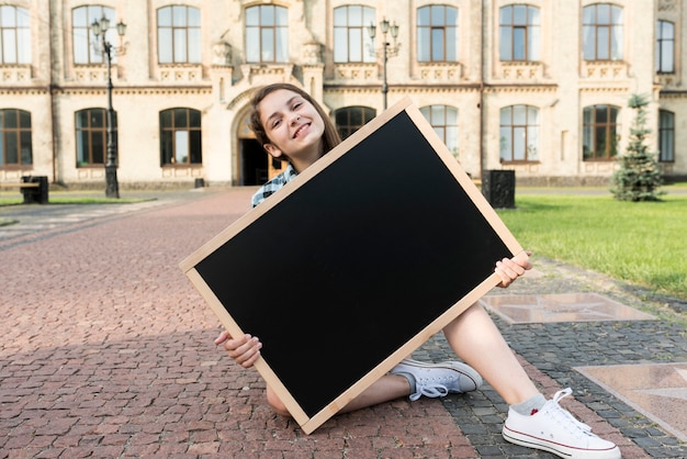 Front view teenage girl holding blackboard