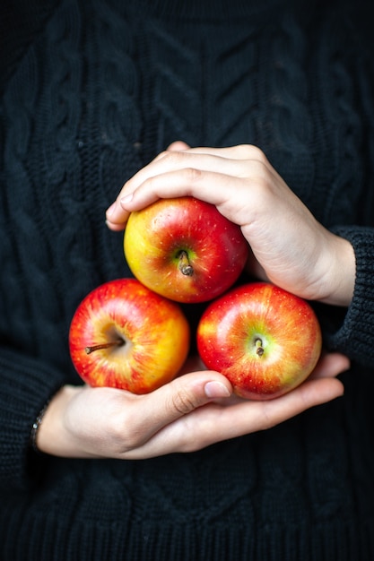 Front view three ripe red apples in woman hands