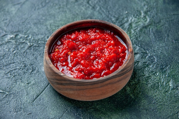 Free Photo front view tomato sauce inside brown plate on dark-blue surface tomato red color seasoning pepper salt