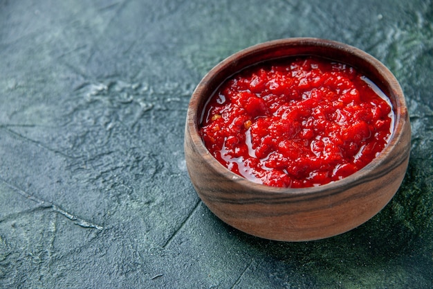 Free photo front view tomato sauce inside brown plate on the dark-blue surface tomato red color seasoning pepper salt