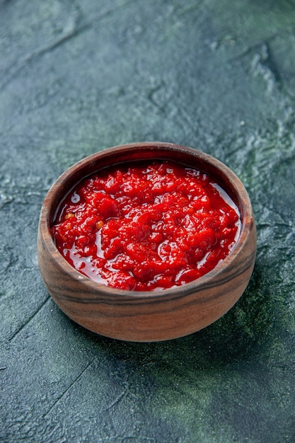 Front view tomato sauce inside brown plate on a dark-blue table tomato red color seasoning pepper salt