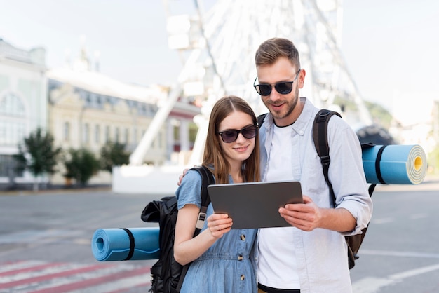 Free photo front view of tourist couple looking at tablet