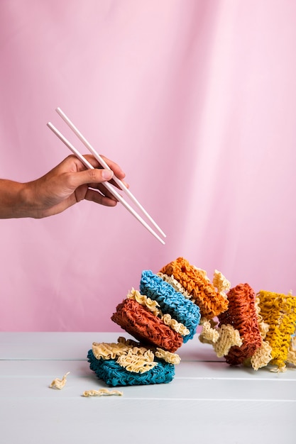 Free Photo front view tower of colorful ramen noodles and hand with chopsticks