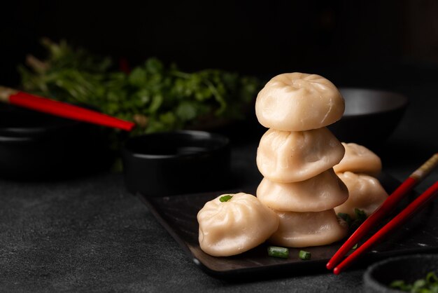 Front view of traditional asian dumplings with chopsticks and herbs