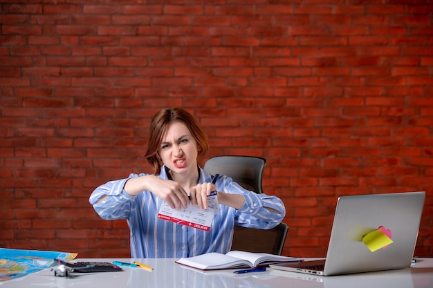 Front view travel agent sitting behind her working place holding plane tickets assistant map service indoors managers world operator agency