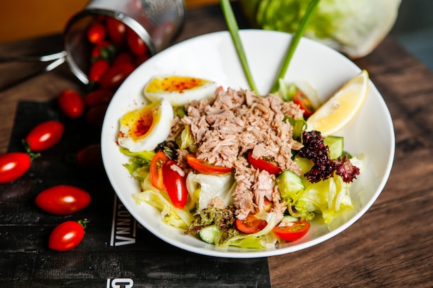 Free Photo front view tuna salad with tomatoes and boiled egg in a plate with lemon