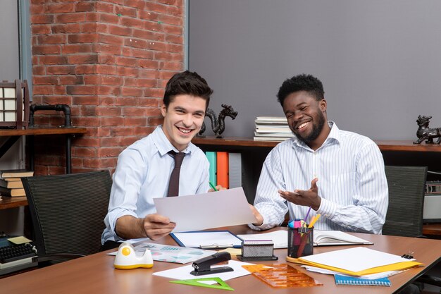 Front view two blissful businessmen working together office stuffs on table