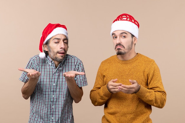 Front view two guys with santa hats confusing on beige isolated background