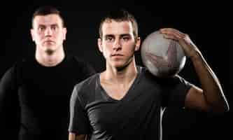 Free photo front view of two male rugby players posing with ball