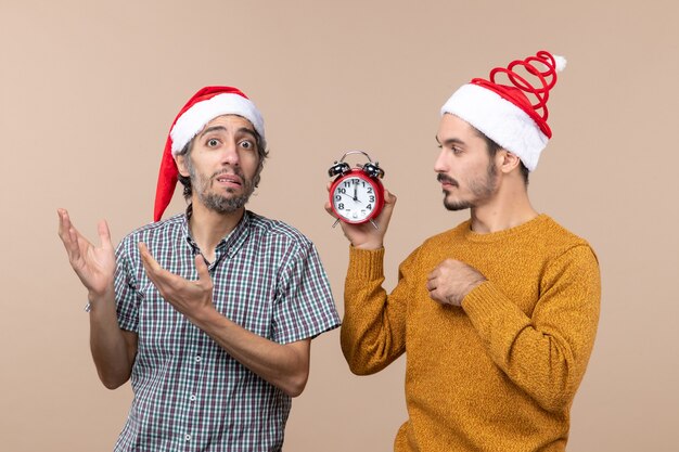 Free Photo front view two men one holding an alarm clock and the other confusing it on beige isolated background