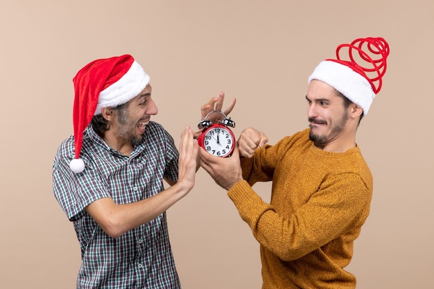 Front view two men trying turn off the alarm clock on beige isolated background