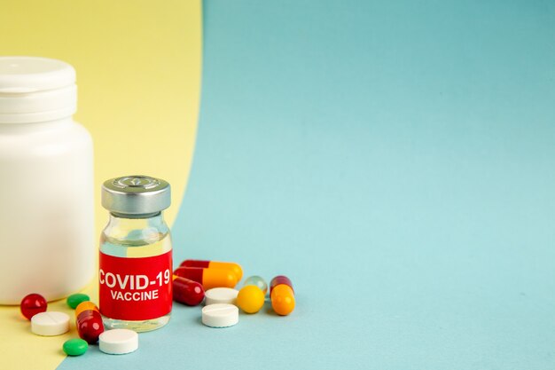 front view vaccine against covid with different pills on yellow-blue background